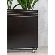 Matt fekete Line-Up kaspó gurulós alátéten, zöld növényekkel, beltéri betonpadlón