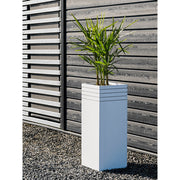 Modern kültéri környezetben elhelyezett fehér Line-Up kaspó zöld levelű növénnyel, fa falburkolat mellett