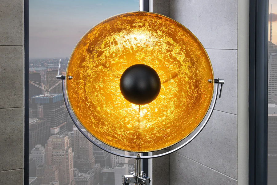 Háromlábú, aranyszínű design állólámpa.