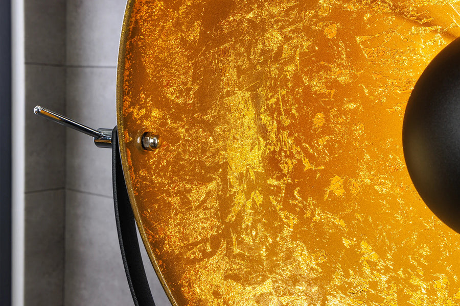 Háromlábú, aranyszínű design állólámpa.