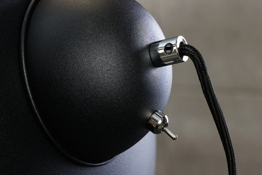 Háromlábú, ezüstszínű design állólámpa.