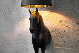 Black Beauty lófigurás állólámpa világítva, fehér falnál