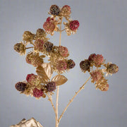 Részletfotó aranyszínű mű szeder ágról, bordó és arany bogyókkal, csillogó díszítéssel.