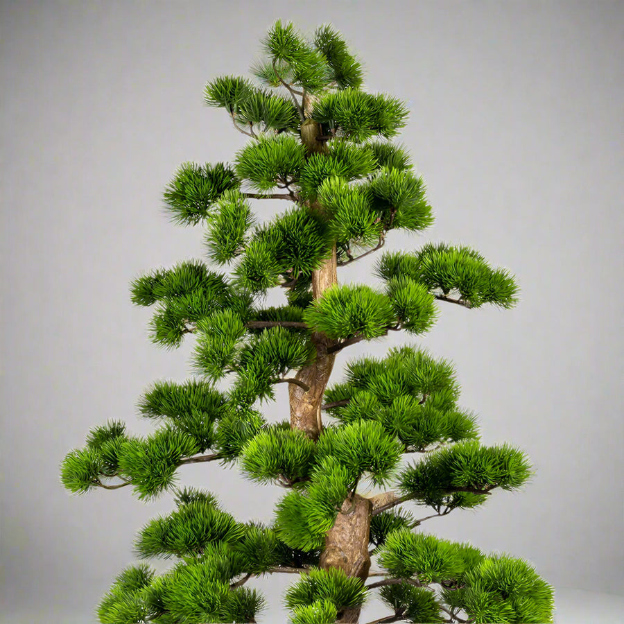 Zöld színű, mű fenyő bonsai fa, fekete színű műanyag cserépben.