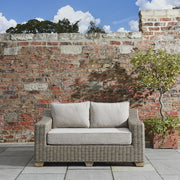 2 személyes, bézs színű műrattan kerti kanapé.