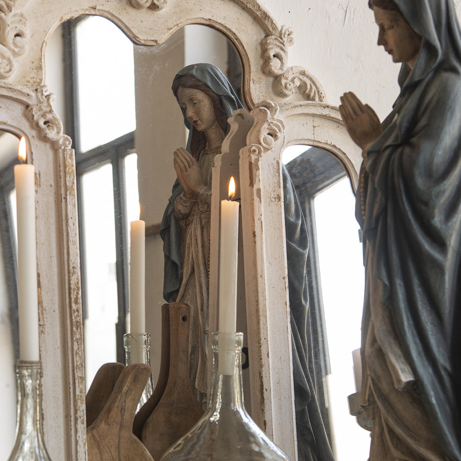 Közelkép a Chateau tükör bal oldali paneljéről, a díszített fa keret finom részleteivel.