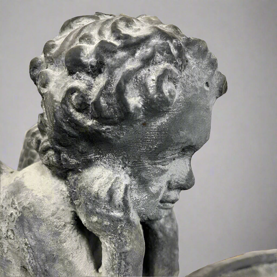 Könyöklő puttófigura részlet a Château Jardin öntöttvas kaspóról, finoman kidolgozott antik felülettel és klasszikus bájjal.