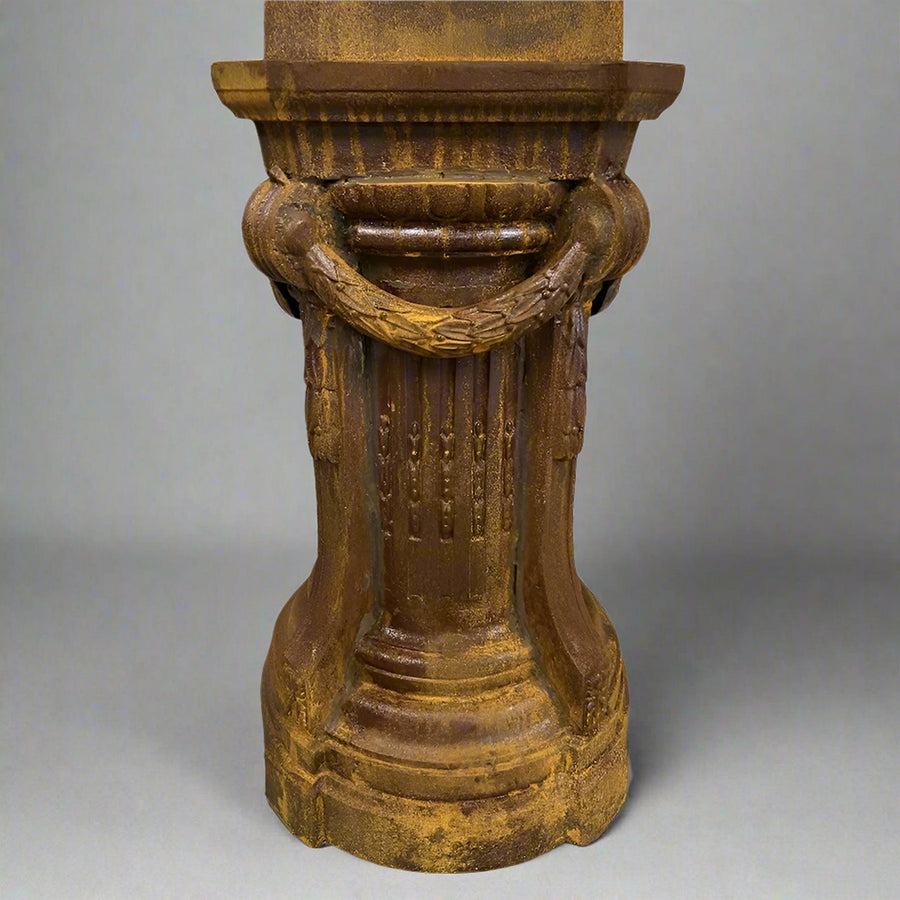 Öntöttvas posztamens részlet, füzérmintás dekorációval és patinás rozsdás felülettel.