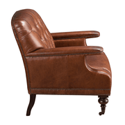 Oldalnézet – Chester konyakbarna bőrfotel elegáns görgős lábakkal.