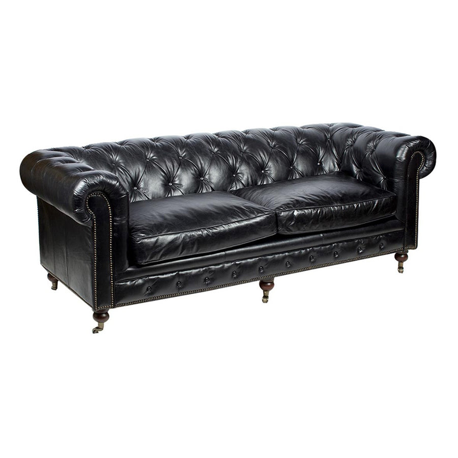 Fekete Chesterfield kanapé enyhén döntött szögből, jól látható ívelt karfákkal és részletgazdag bőrborítással.