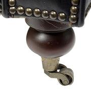 Makrófotó a kanapé görgős lábáról, antikolt fém és fa kombinációval, elegáns részletmegoldással.