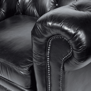 Közeli kép a fotel karfájáról és a szegecselt szegélyezés részleteiről.