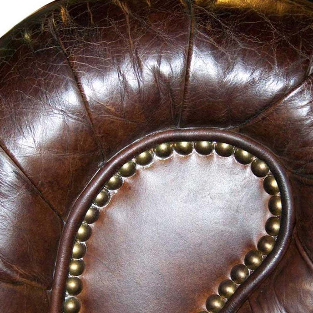 Közelkép a bőrkárpit patinás felületéről és az antikolt rézszínű szegecselésről a Chesterfield Cigar kanapén.