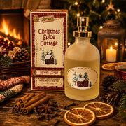 Karácsonyi hangulatú enteriőrben elhelyezett CHRISTMAS SPICE COTTAGE lakásparfüm fahéjjal, naranccsal és ünnepi dekorációval a kandalló előtt.