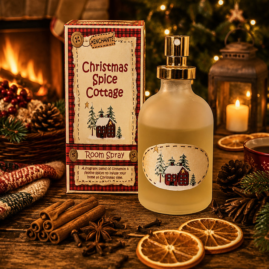 Karácsonyi hangulatú enteriőrben elhelyezett CHRISTMAS SPICE COTTAGE lakásparfüm fahéjjal, naranccsal és ünnepi dekorációval a kandalló előtt.