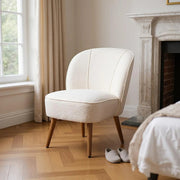 Bézs bouclé klub fotel elegáns hálószobai enteriőrben, természetes fényben.