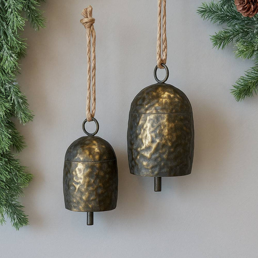 Két méretű Doré antik réz kolomp falon lógva, jutakötéllel és rusztikus fenyőág dekorációval, karácsonyi hangulatban.