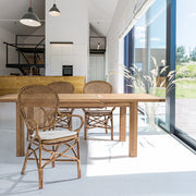 Világos, modern enteriőrben elhelyezett mézbarna rattan székek étkezőasztal körül.