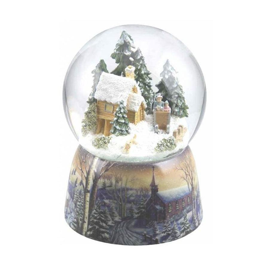 Karácsonyi zenélő hógömb, téli erdei házikó előtt szánkózó családdal.