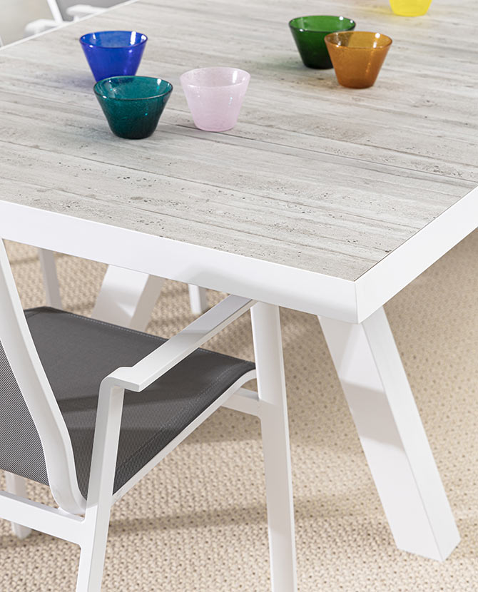 Krém színű kortárs kerti étkezőasztal színes üveg poharakkal.