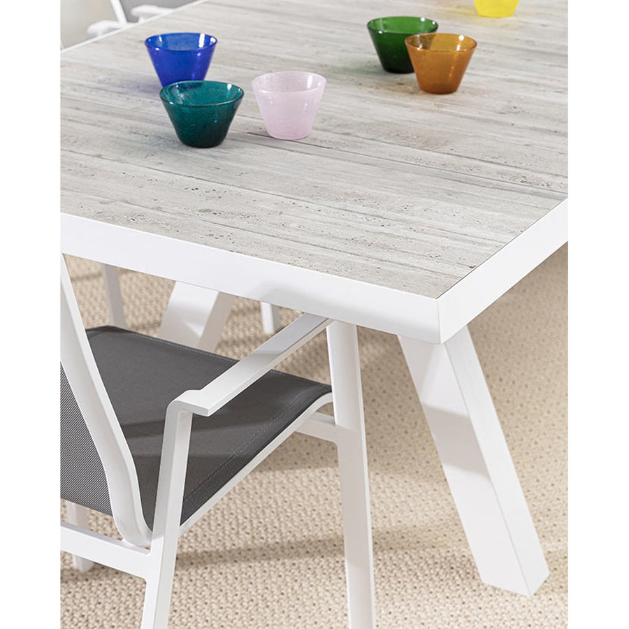 Krém színű kortárs kerti étkezőasztal színes üveg poharakkal.