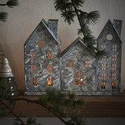 Szürke színű, bádogból készült házikókat formázó lámpás.