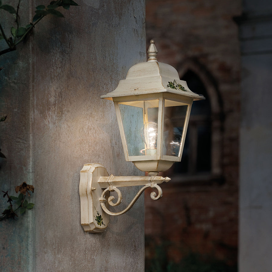 Falra szerelt Ferroluce Classic Gorizia falilámpa fehér színben, kültéri környezetben, vintage stílusú olasz épület falán, világító izzóval.