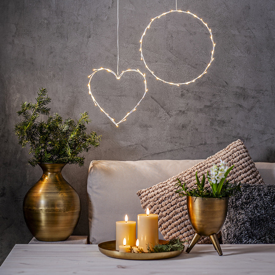 Bézs Flow LED gyertyák tálcán elhelyezve egy modern nappaliban, dekorációs világítással és száraz növényes vázával – meleg, meghitt otthoni hangulat.