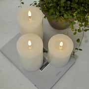 Három fehér LED gyertya a Star Trading Flow kollekcióból egy magazinon, növénnyel dekorálva, letisztult enteriőrben.