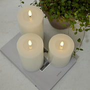 Három fehér LED gyertya a Star Trading Flow kollekcióból egy magazinon, növénnyel dekorálva, letisztult enteriőrben.