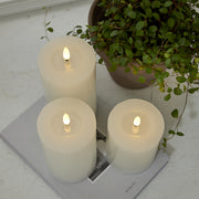 Három fehér LED gyertya a Star Trading Flow kollekcióból egy magazinon, növénnyel dekorálva, letisztult enteriőrben.