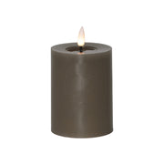 Szürkésbarna, henger alakú LED gyertya meleg fehér lánggal, fehér háttér előtt, 12,5 cm magas kivitelben.