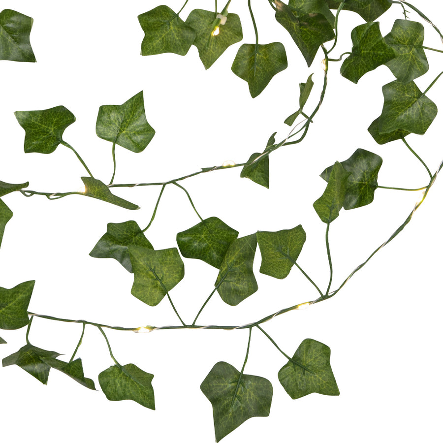 Közelről fotózott Hedera LED-es mű borostyán girland, zöld levelekkel és apró, meleg fehér fényű LED világítással fehér háttér előtt.