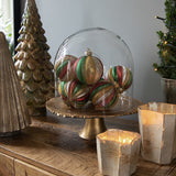 Heritage üveg karácsonyfadíszek dekorációként üvegbúra alatt, vintage stílusú piros, zöld és arany gömbök ünnepi hangulatban