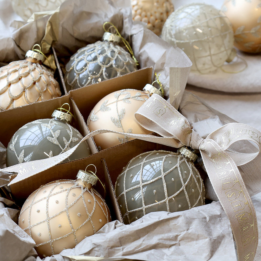 Kézzel készített pezsgőszínű üvegdíszek közelről, díszdobozban, masnis szalaggal átkötve.