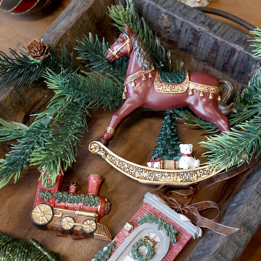 NOÉL bordó karácsonyi hintaló figura ünnepi enteriőrben, fenyőágak között