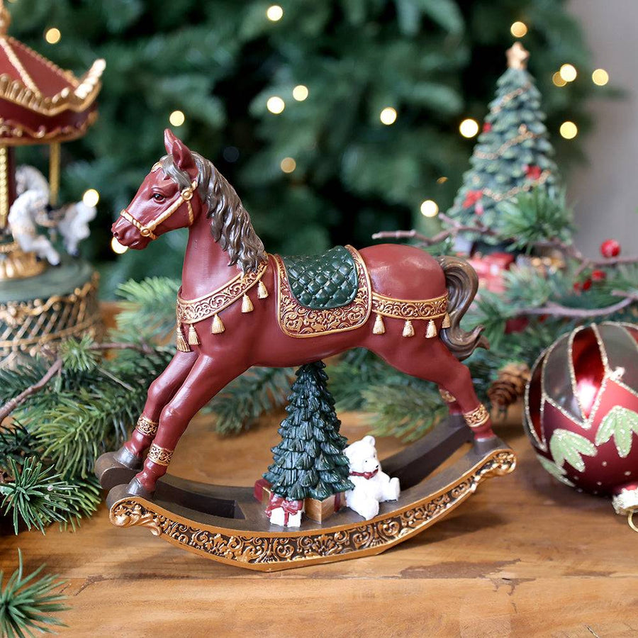 NOÉL bordó karácsonyi hintaló figura ünnepi enteriőrben, fenyőágak között