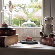 Antikolt maci figura vintage dekorációval, könyvek és üveg búra mellett.