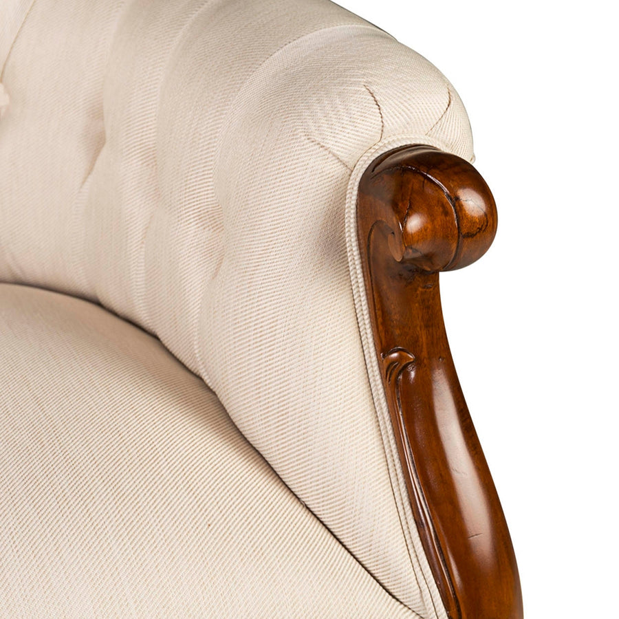 Közelkép a fotel kartámaszáról, bézs szövet és mahagónifa ívelt találkozásával.