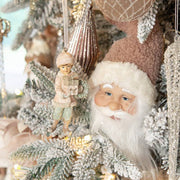 Heritage pink kisfiú karácsonyfadísz elhelyezve egy feldíszített, havas karácsonyfán, nosztalgikus dekorációban.