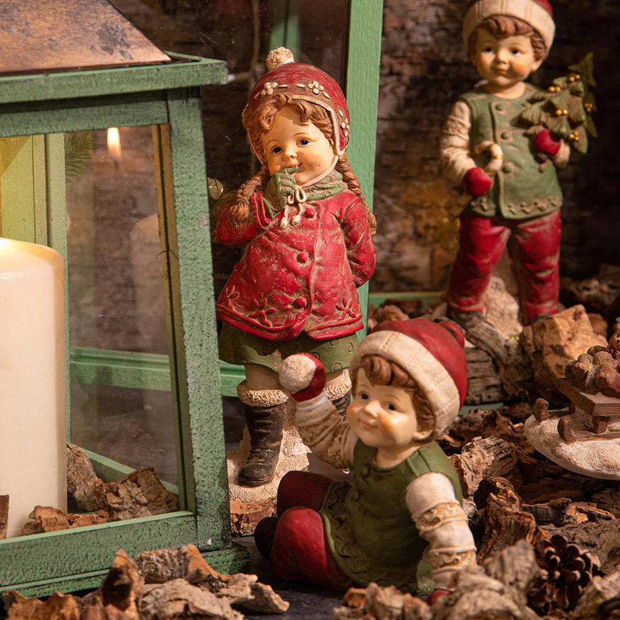 HERITAGE karácsonyi téli kisfiú figura díszletben, zöld lámpás és ünnepi kiegészítők között.