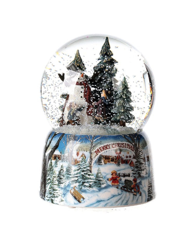 Karácsonyi zenélő-forgó hógömb, téli havas erdőben hóembert építő gyerekekkel.