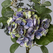 Részletfotó kék vegyes mű hortenzia csokorról, természetes hatású virágfejekkel és zöldekkel.