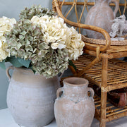 Hortenzia kompozíció terrakotta vázában, zöldes és krémszínű szálak keverékével.