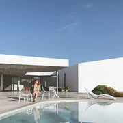 Fehér műanyag kerti bútorok medence partján.