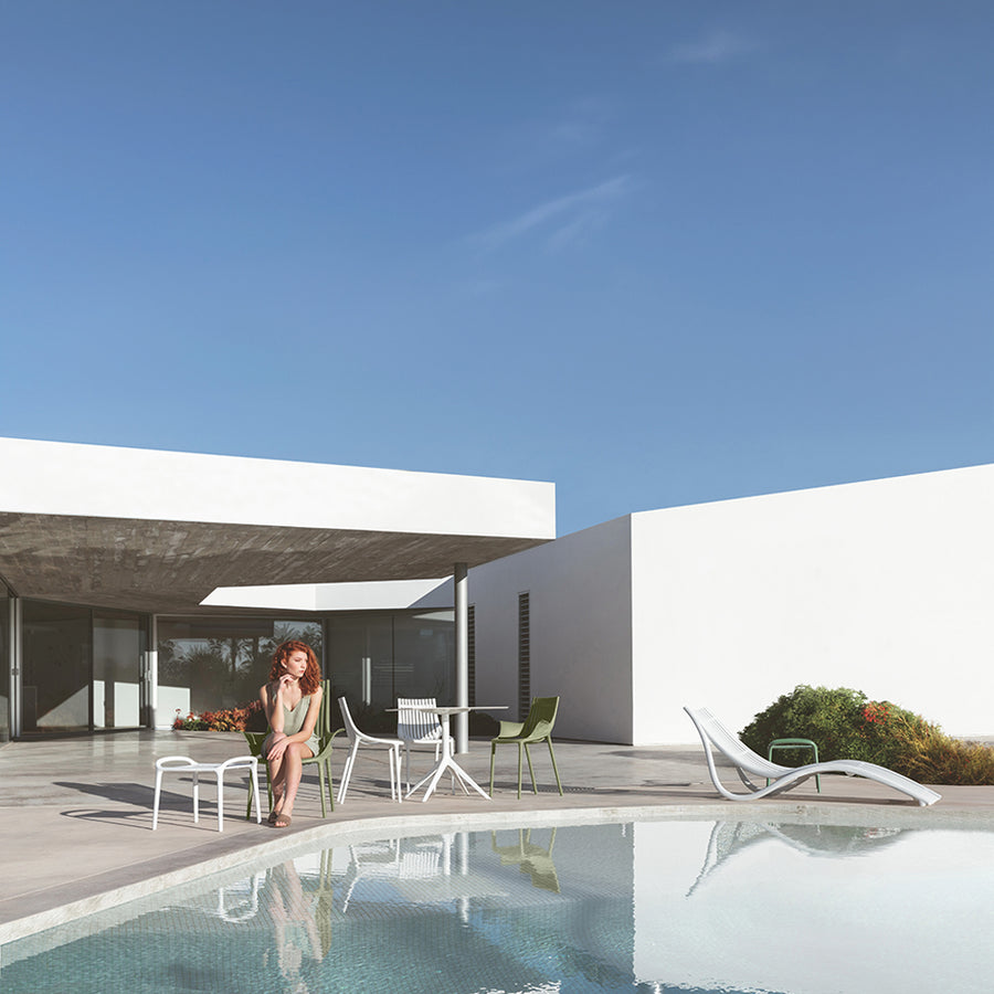 Fehér műanyag kerti bútorok medence partján.