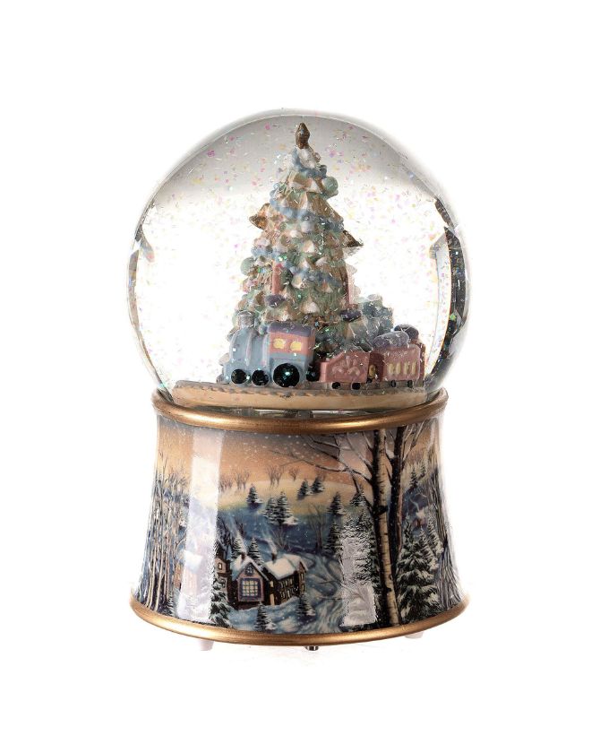 Karácsonyi zenélő-forgó csillámos hógömb, ünnepi karácsonyfával körülötte játék mozdonnyal.