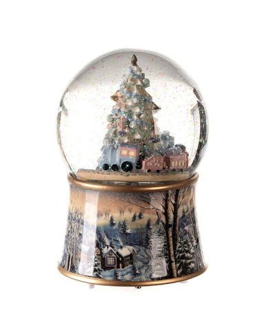 Karácsonyi zenélő-forgó csillámos hógömb, ünnepi karácsonyfával körülötte játék mozdonnyal.