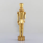 Arany színárnyalatú, faragott fahatású karácsonyi diótörő figura.