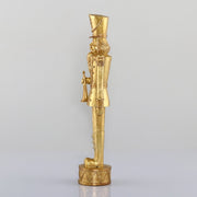 Arany színárnyalatú, faragott fahatású karácsonyi diótörő figura.